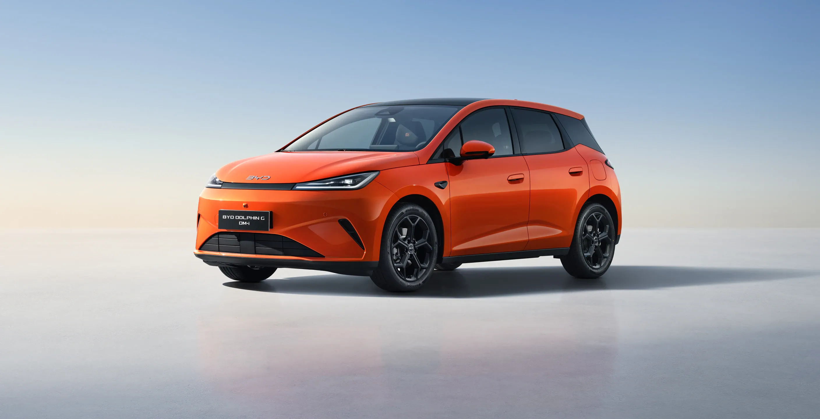 Orange BYD Dolphin G DM-i side profile view showing 18-inch alloy wheels