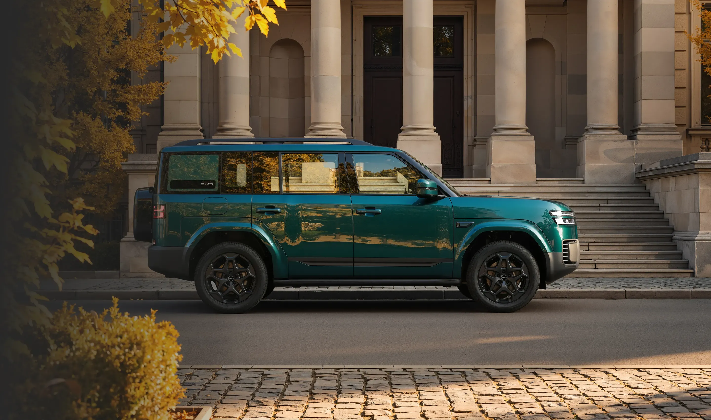 Teal BYD Ti7 SUV parked beside a classical building