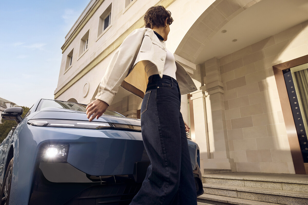 Woman standing beside light blue Leapmotor B10 front quarter view