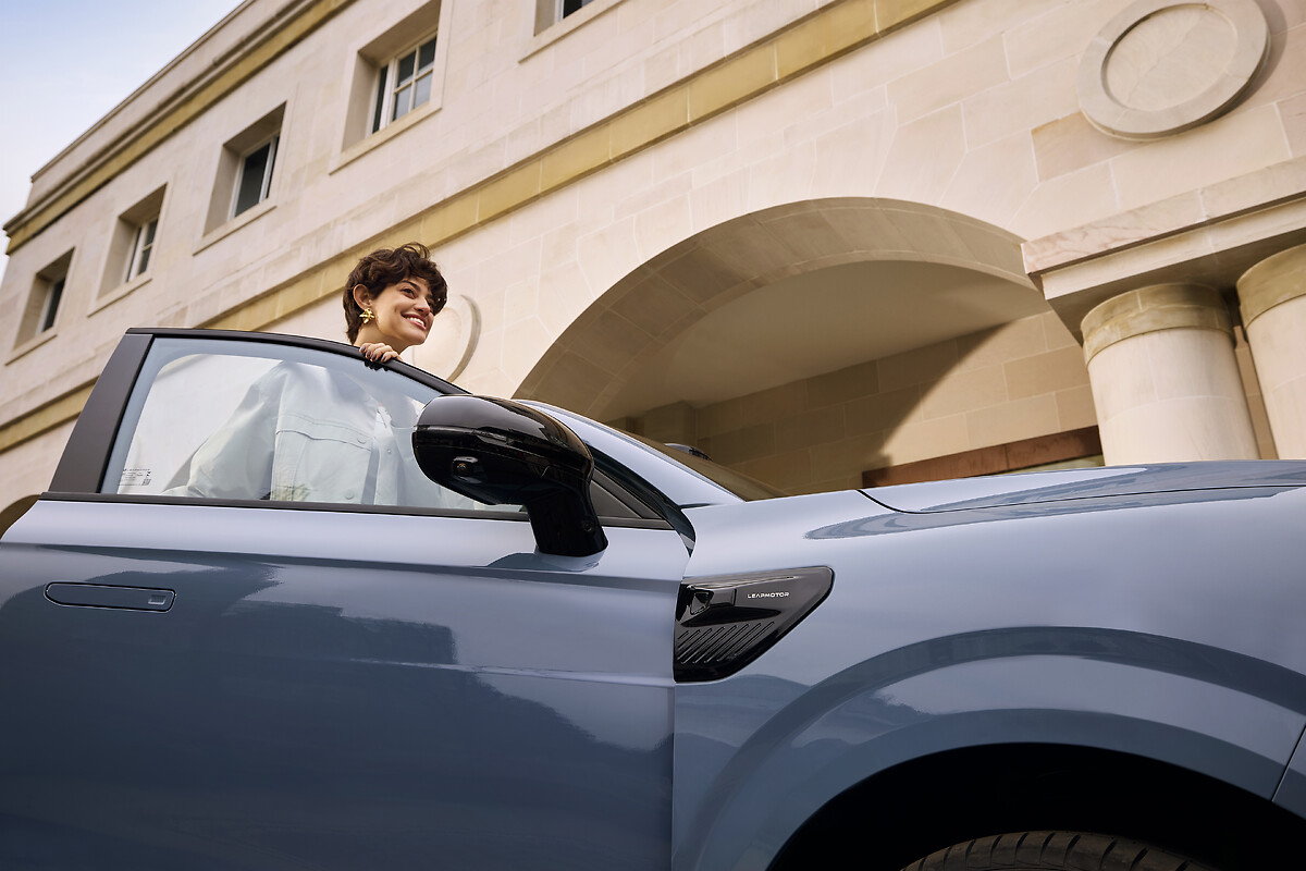 Woman leaning out of light blue Leapmotor B10 window showing flush door handles