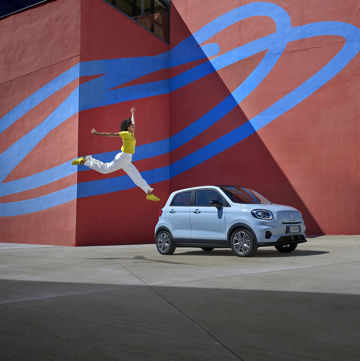 White Leapmotor T03 parked in front of a colourful mural showing its front design