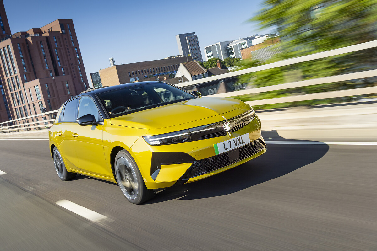 Yellow Vauxhall Astra driving on urban highway with buildings